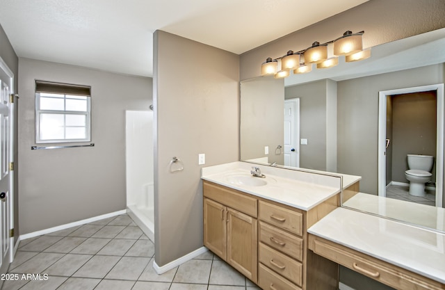 bathroom featuring tile patterned floors, baseboards, toilet, and vanity