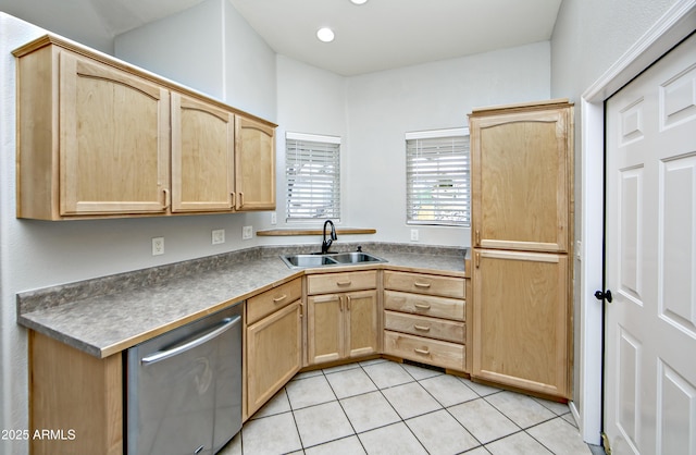 kitchen featuring dark countertops, a sink, light brown cabinets, light tile patterned flooring, and stainless steel dishwasher