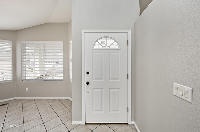 entryway featuring lofted ceiling, light tile patterned floors, and baseboards