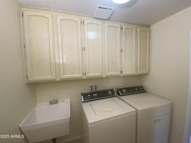 clothes washing area featuring cabinet space, washing machine and dryer, and a sink