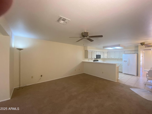 unfurnished living room with light tile patterned floors, light colored carpet, visible vents, and ceiling fan