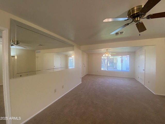 carpeted spare room with baseboards, visible vents, and ceiling fan