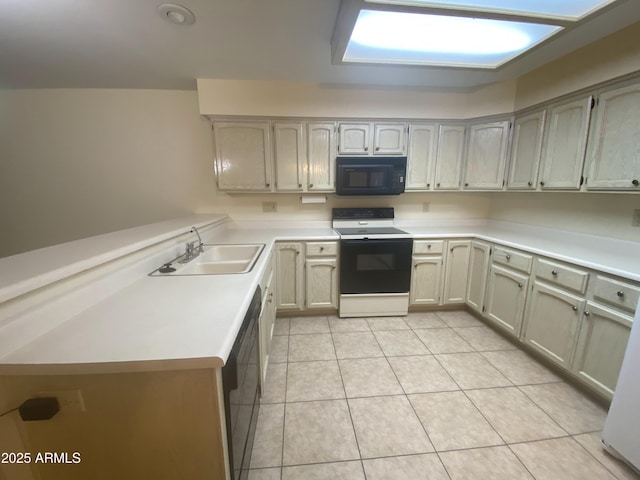 kitchen with a peninsula, light tile patterned flooring, a sink, black appliances, and light countertops