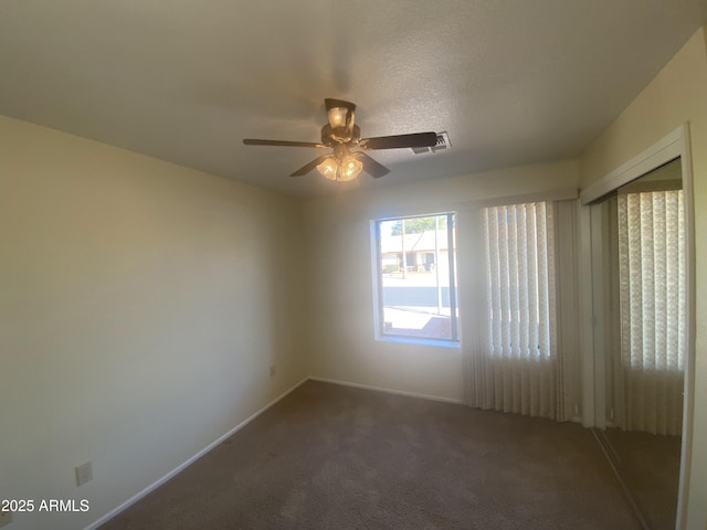 empty room featuring visible vents, carpet floors, baseboards, and a ceiling fan