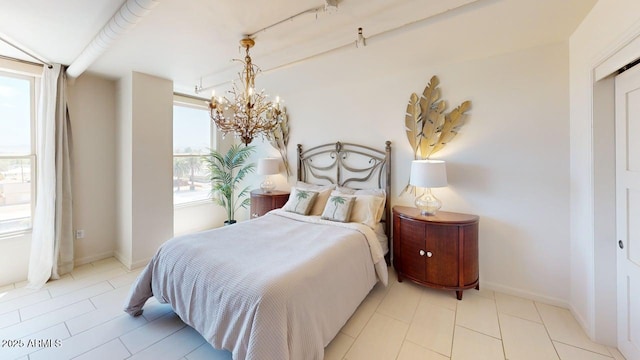 bedroom featuring multiple windows, a chandelier, and baseboards