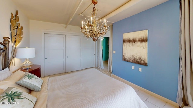 bedroom with a chandelier, light tile patterned floors, a closet, and baseboards
