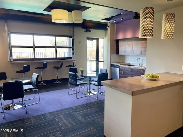 kitchen featuring a sink, dishwasher, dark carpet, and decorative light fixtures