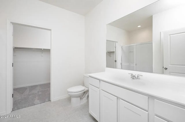 bathroom featuring tile patterned floors, vanity, toilet, and a shower with door