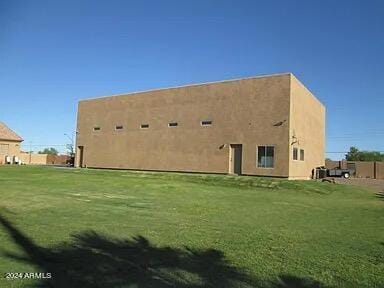 rear view of property with stucco siding and a yard