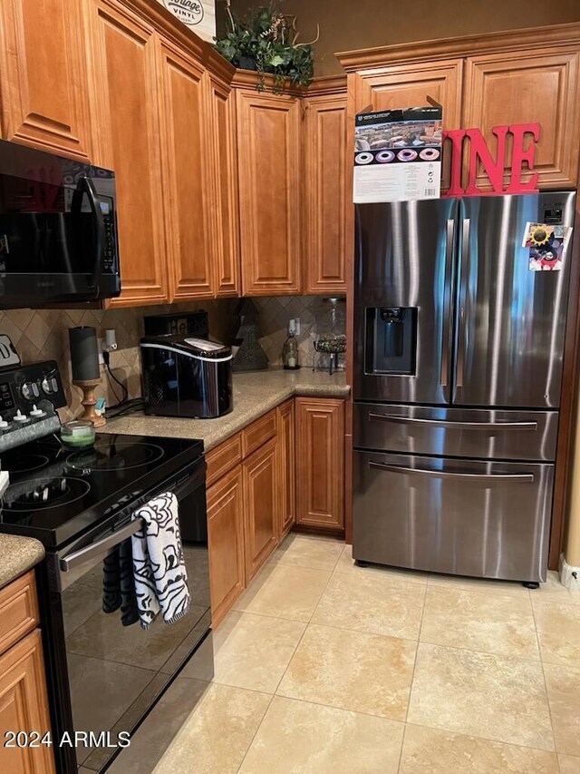 kitchen featuring light tile patterned flooring, brown cabinets, black appliances, and decorative backsplash