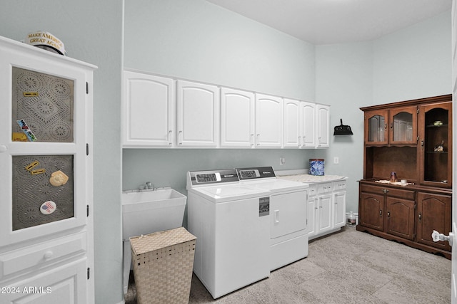 laundry room featuring washing machine and clothes dryer, sink, and cabinets