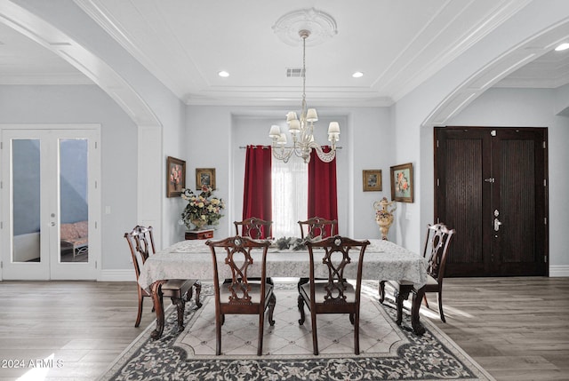 dining room with a chandelier, french doors, light wood-type flooring, and crown molding