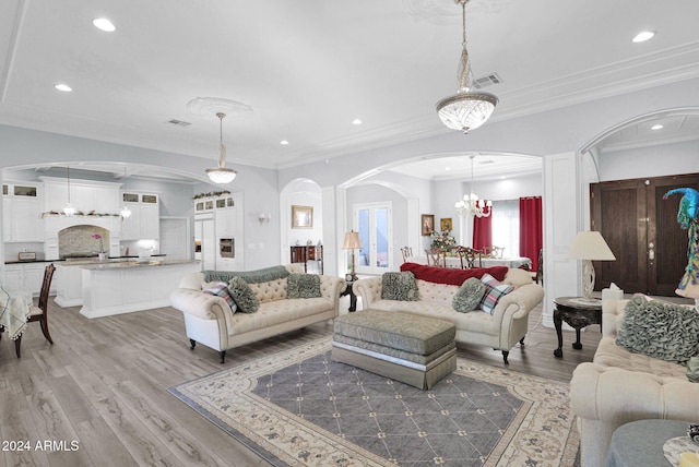 living room with light wood-type flooring, an inviting chandelier, and crown molding