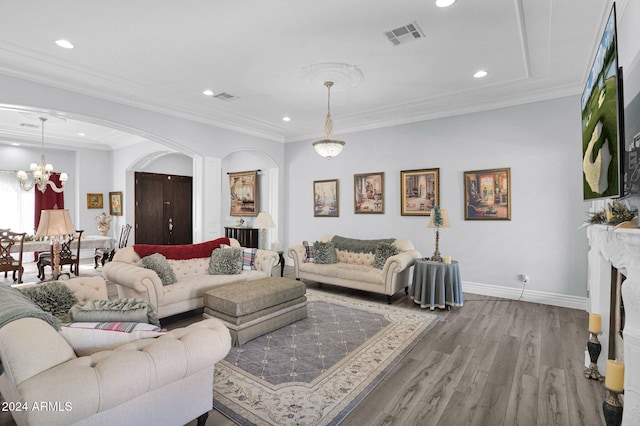 living room featuring hardwood / wood-style flooring, ornamental molding, and a chandelier