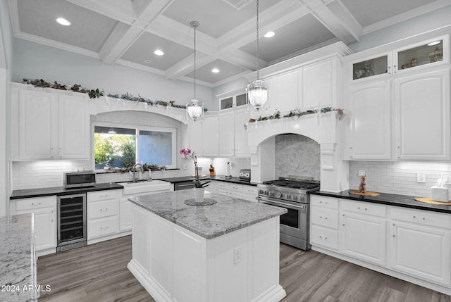 kitchen featuring white cabinetry, stainless steel appliances, wine cooler, dark stone countertops, and a kitchen island