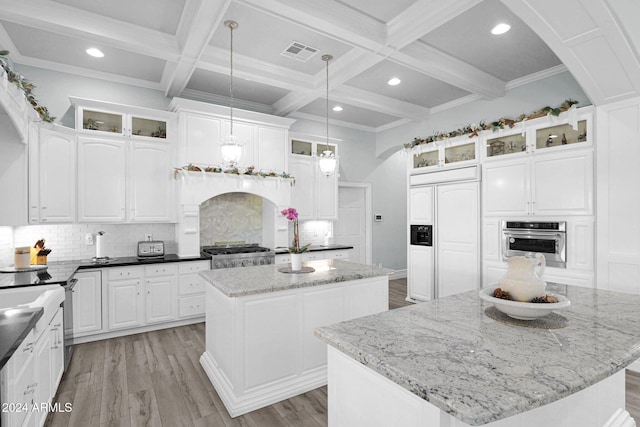 kitchen featuring pendant lighting, a center island, dark stone counters, oven, and paneled refrigerator