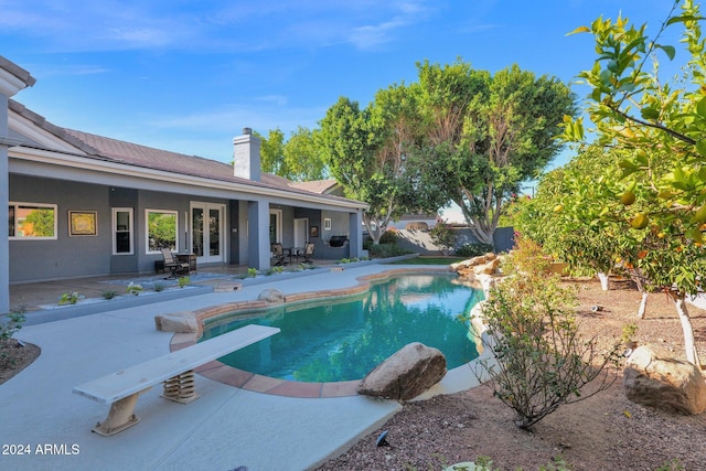 view of pool featuring a diving board and a patio