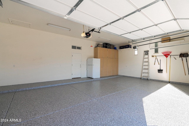 garage featuring white refrigerator and a garage door opener