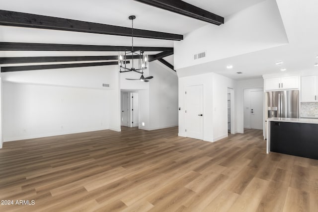 unfurnished living room with lofted ceiling with beams, wood-type flooring, and an inviting chandelier