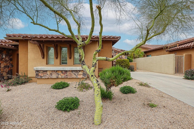 view of front of property featuring fence, a gate, stucco siding, and a tiled roof