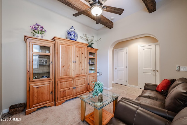 living room with baseboards, arched walkways, beam ceiling, and a ceiling fan