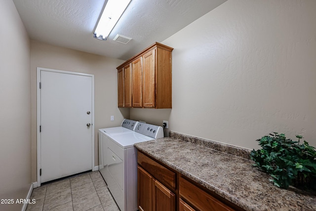 washroom with washing machine and clothes dryer, light tile patterned flooring, a textured ceiling, visible vents, and cabinet space