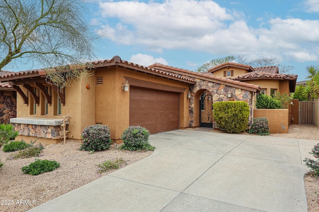 mediterranean / spanish-style home featuring driveway, a gate, stucco siding, fence, and a garage
