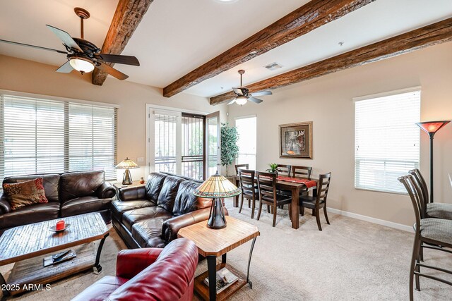 living area with a ceiling fan, light carpet, beam ceiling, and a wealth of natural light