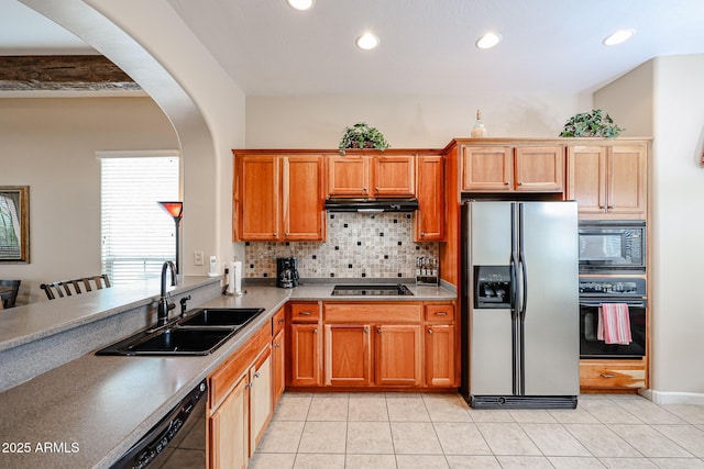 kitchen featuring a sink, tasteful backsplash, under cabinet range hood, black appliances, and arched walkways