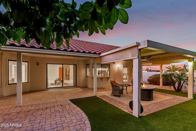 9809 W Behrend Dr, Peoria, AZ 85382 - back of house at dusk with an outdoor fire pit, a patio, a tile roof, and fence
