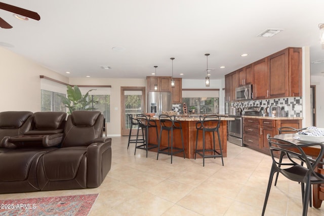 9809 W Behrend Dr, Peoria, AZ 85382 - kitchen featuring stainless steel appliances, open floor plan, a kitchen breakfast bar, decorative backsplash, and ceiling fan