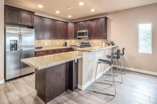 6145 E Cave Creek Rd Unit 203, Cave Creek, AZ 85331 - kitchen featuring appliances with stainless steel finishes, a peninsula, a kitchen breakfast bar, dark brown cabinetry, and baseboards