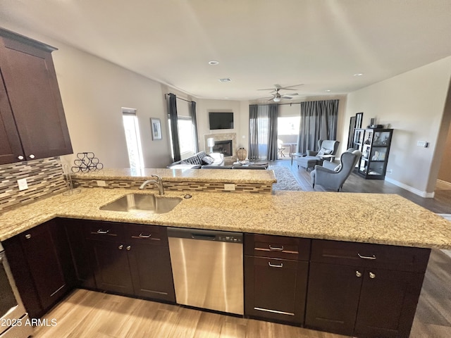 6145 E Cave Creek Rd Unit 203, Cave Creek, AZ 85331 - kitchen with stainless steel dishwasher, a peninsula, a ceiling fan, a glass covered fireplace, and light stone countertops