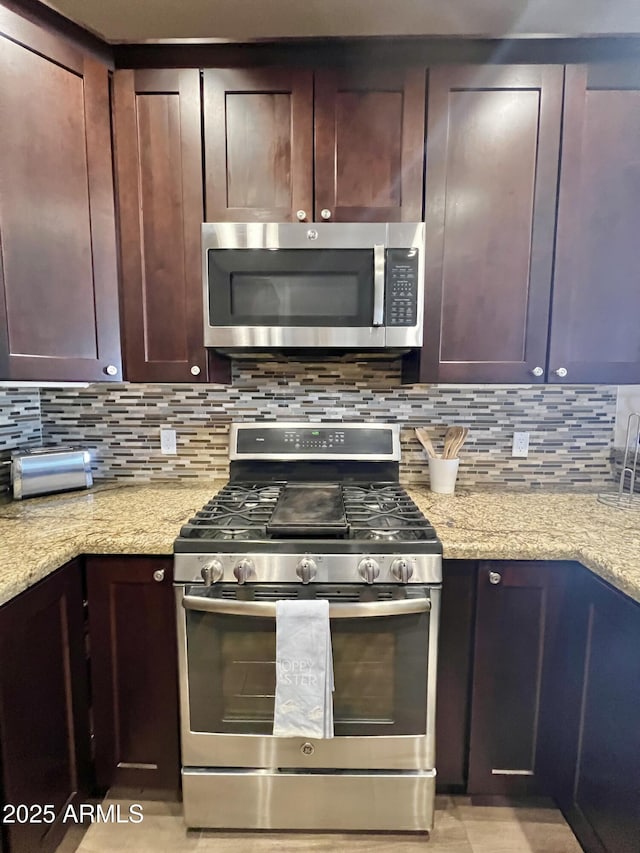 6145 E Cave Creek Rd Unit 203, Cave Creek, AZ 85331 - kitchen featuring appliances with stainless steel finishes, backsplash, light stone counters, and dark brown cabinetry