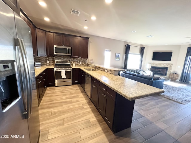6145 E Cave Creek Rd Unit 203, Cave Creek, AZ 85331 - kitchen featuring stainless steel appliances, a peninsula, dark brown cabinetry, open floor plan, and backsplash