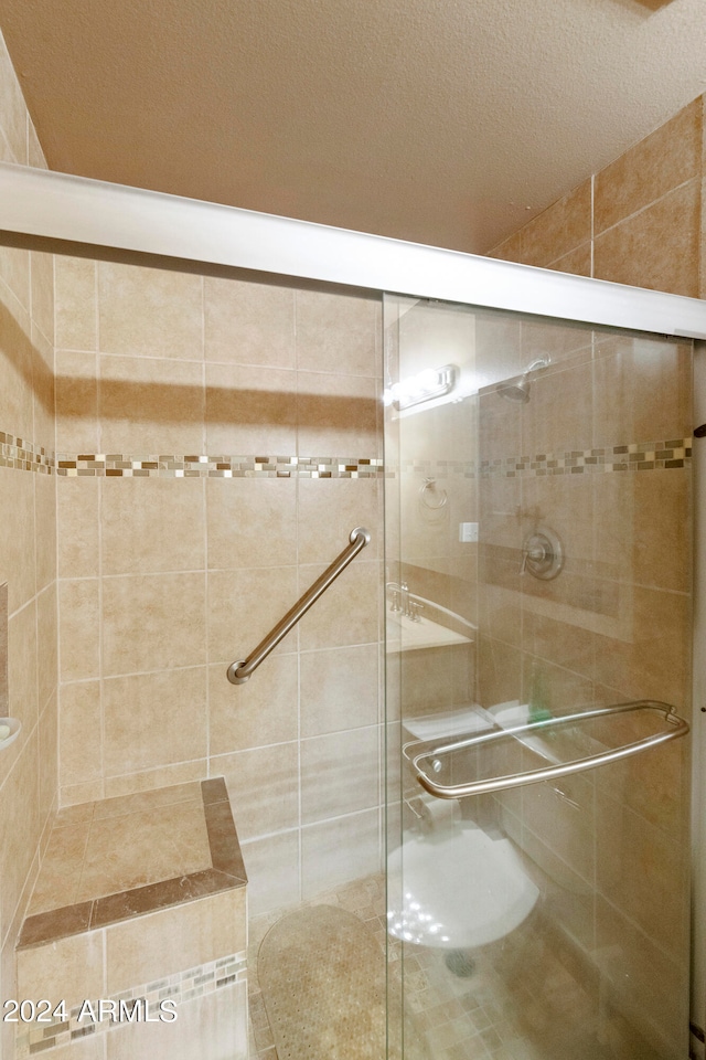 bathroom with tile patterned flooring, a textured ceiling, and walk in shower