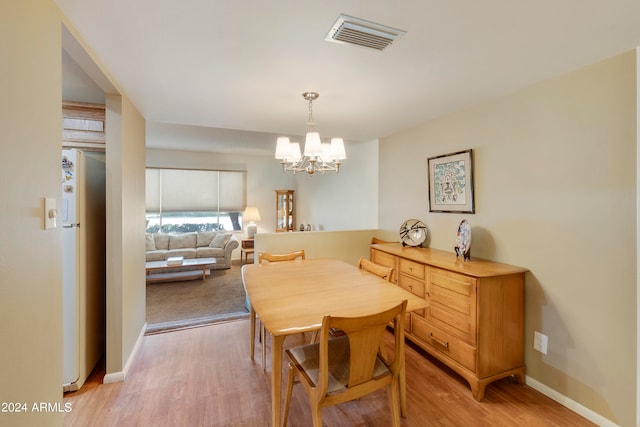 dining room with light wood-type flooring and a notable chandelier