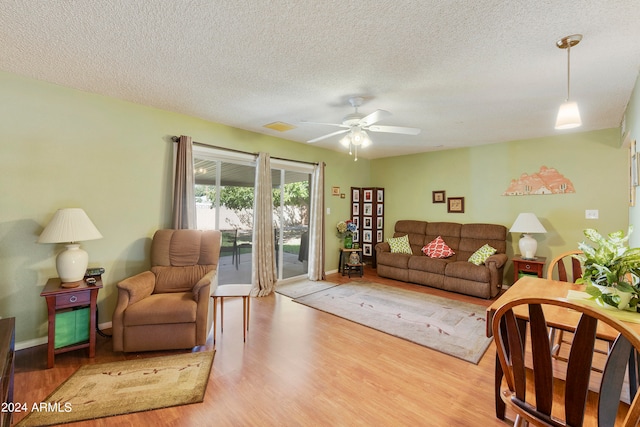 living room featuring wood-type flooring, ceiling fan, and a textured ceiling