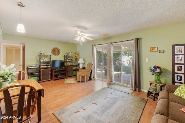 living room featuring ceiling fan, a textured ceiling, and light hardwood / wood-style floors