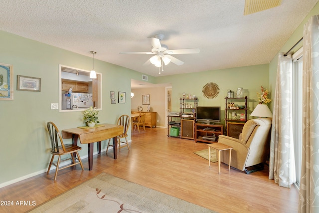 dining space featuring light hardwood / wood-style flooring, ceiling fan, and a textured ceiling