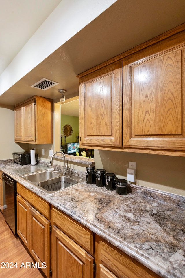 kitchen with light hardwood / wood-style flooring, dishwasher, light stone counters, and sink