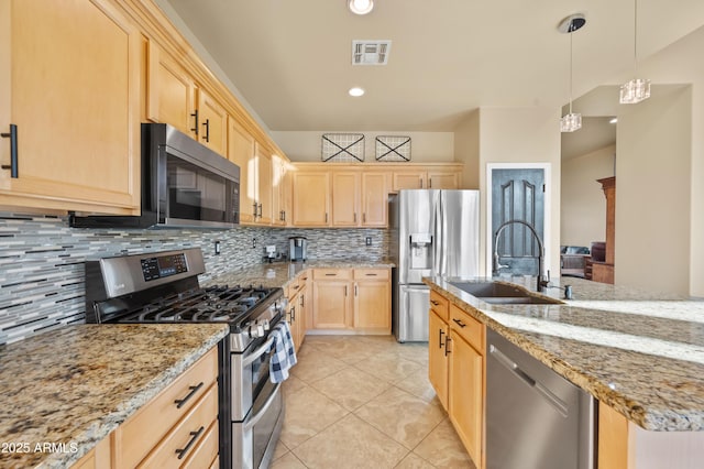 kitchen with sink, light stone counters, decorative light fixtures, light brown cabinets, and appliances with stainless steel finishes