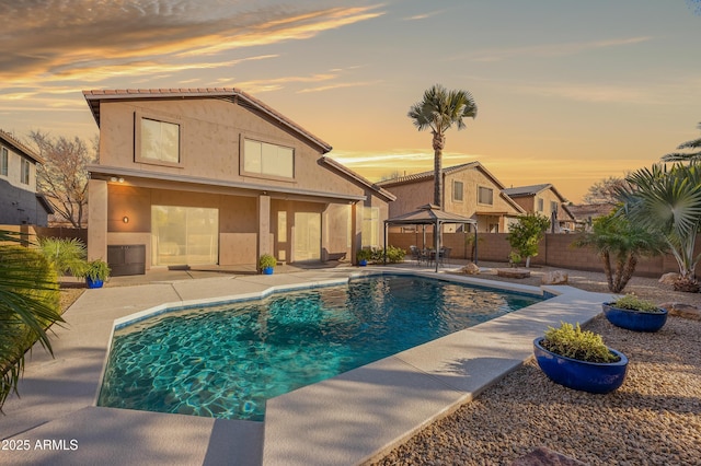 pool at dusk with a gazebo and a patio area