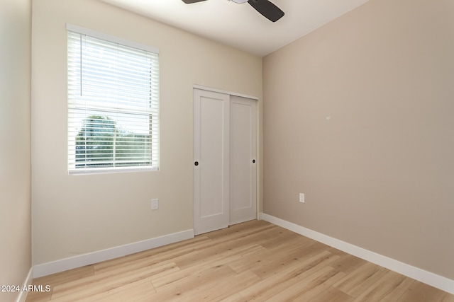 unfurnished bedroom featuring ceiling fan, a closet, and light wood-type flooring