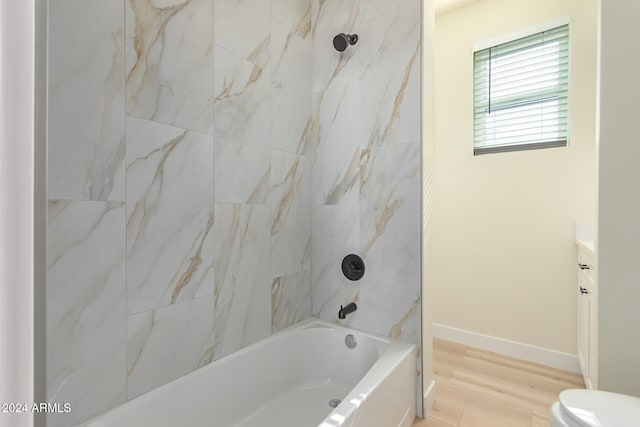 full bathroom featuring hardwood / wood-style floors, tiled shower / bath, toilet, and vanity