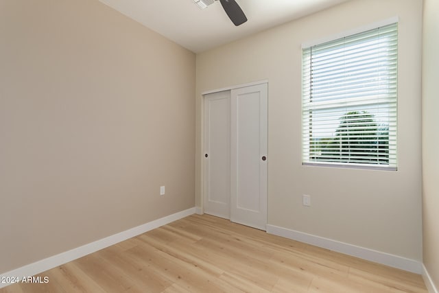 unfurnished bedroom featuring a closet, ceiling fan, multiple windows, and light hardwood / wood-style floors