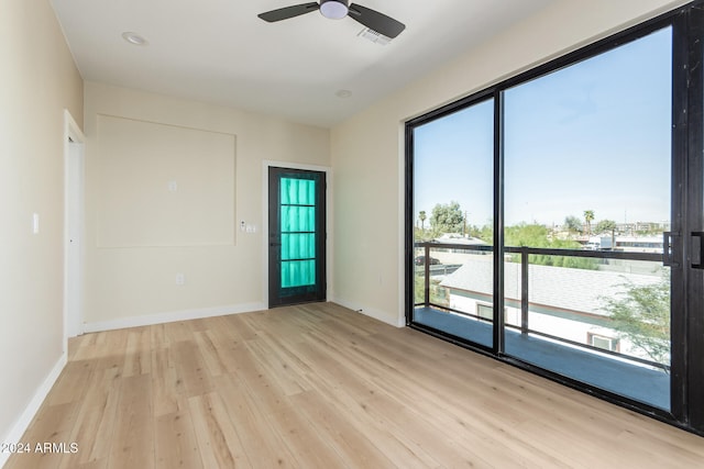 empty room featuring ceiling fan, a water view, and light wood-type flooring