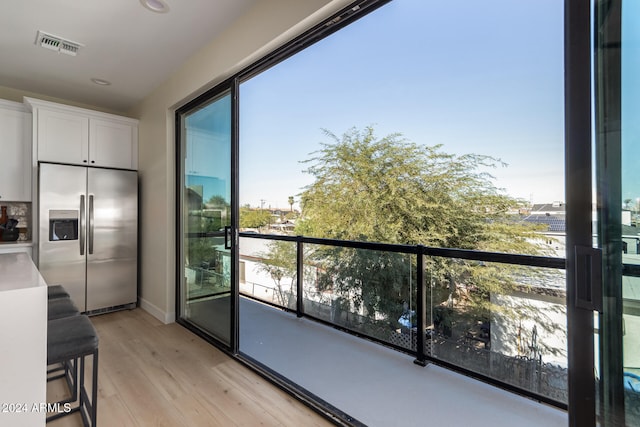 interior space featuring white cabinetry, stainless steel refrigerator with ice dispenser, plenty of natural light, and light hardwood / wood-style flooring