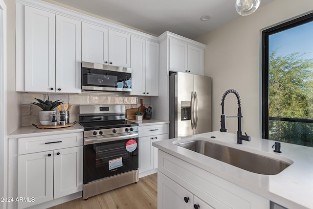 kitchen featuring light hardwood / wood-style floors, sink, appliances with stainless steel finishes, white cabinets, and decorative backsplash