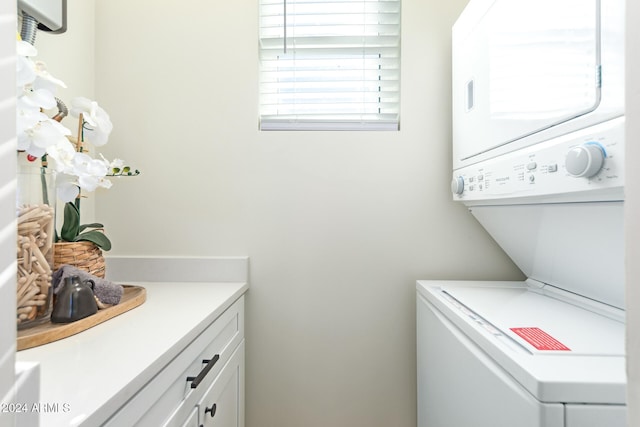 laundry area featuring stacked washer and dryer and cabinets